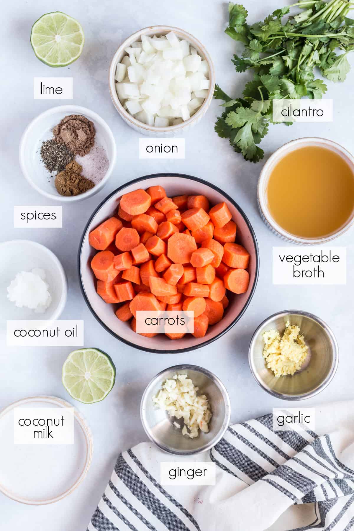 all of the ingredients for carrot soup on a white countertop
