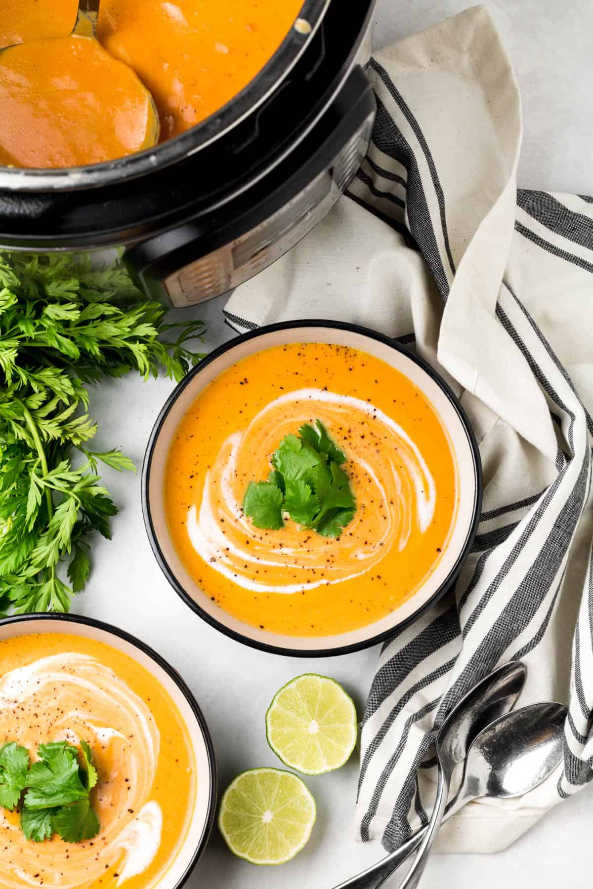a bowl of instant pot carrot soup on the table with lime slices