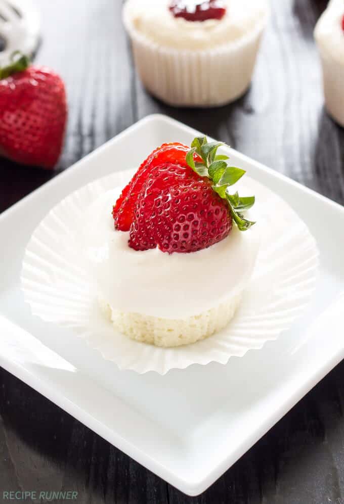 angel food cupcake without paper liner sitting on a plate with a sliced strawberry on top