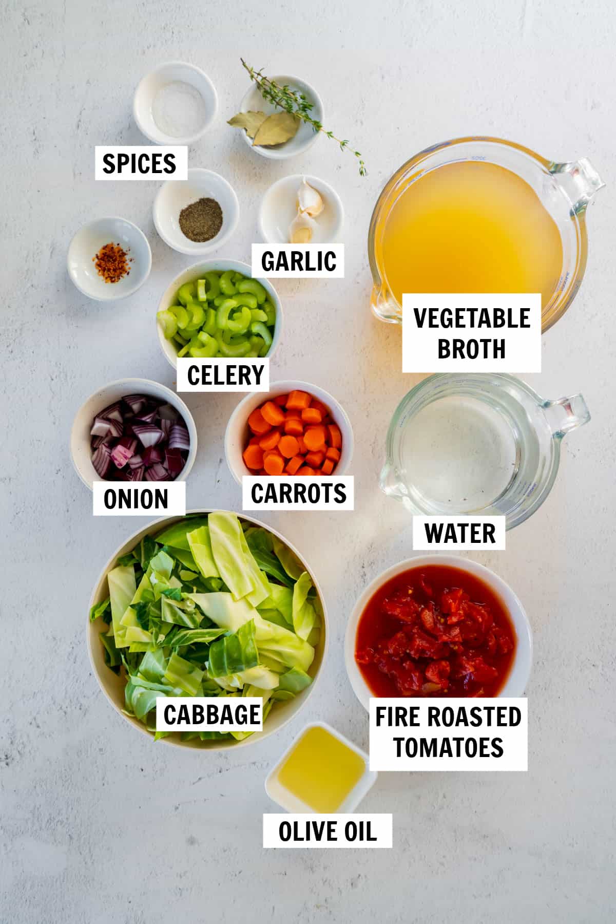 all of the ingredients for cabbage soup in bowls on a white countertop