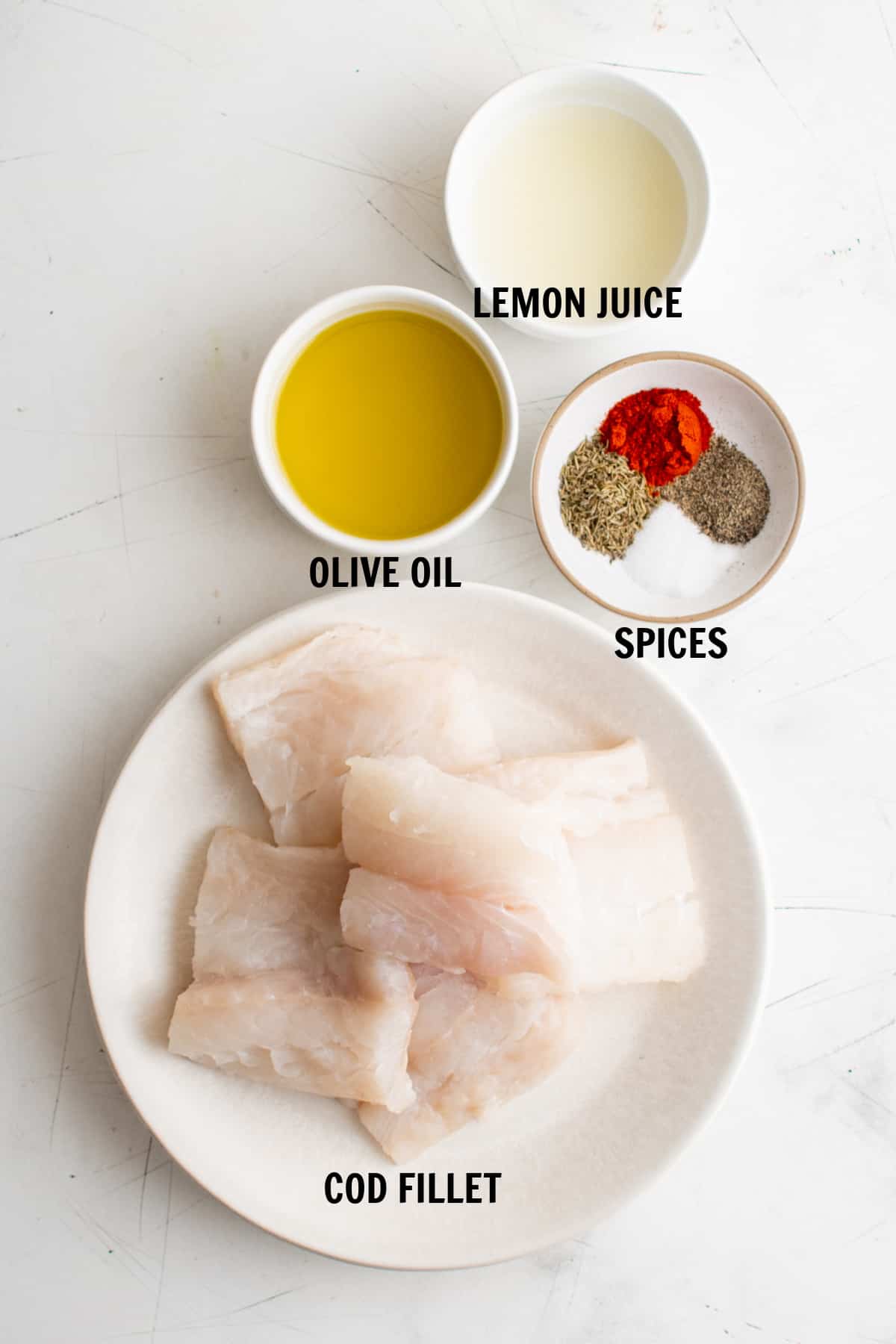all of the ingredients for pan fried cod on a white countertop in bowls