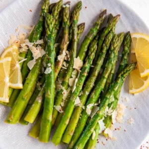 cooked asparagus on a plate with lemon slices