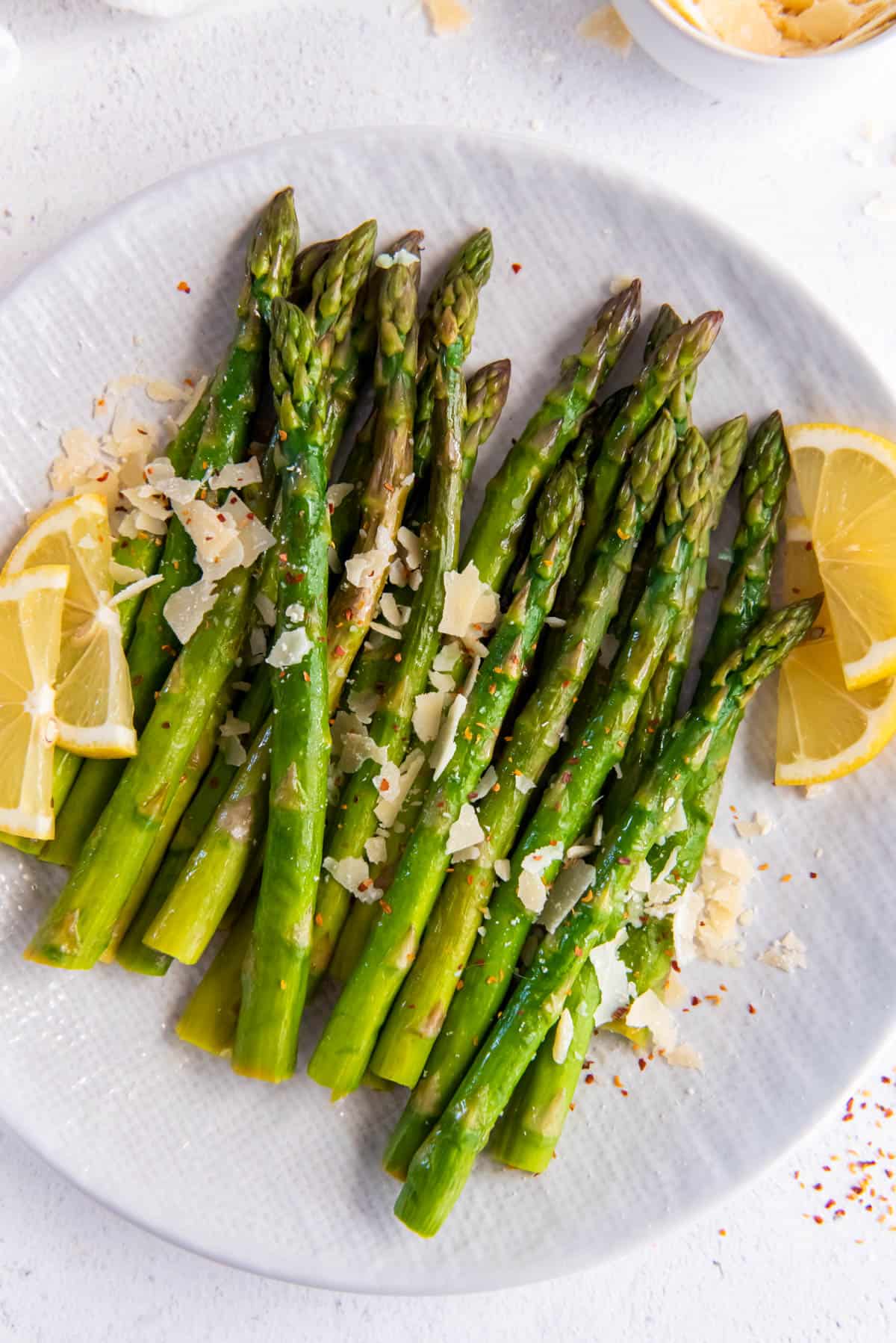 cooked asparagus on a plate with lemon slices