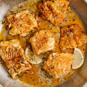 seared cod in a pan with lemon slices