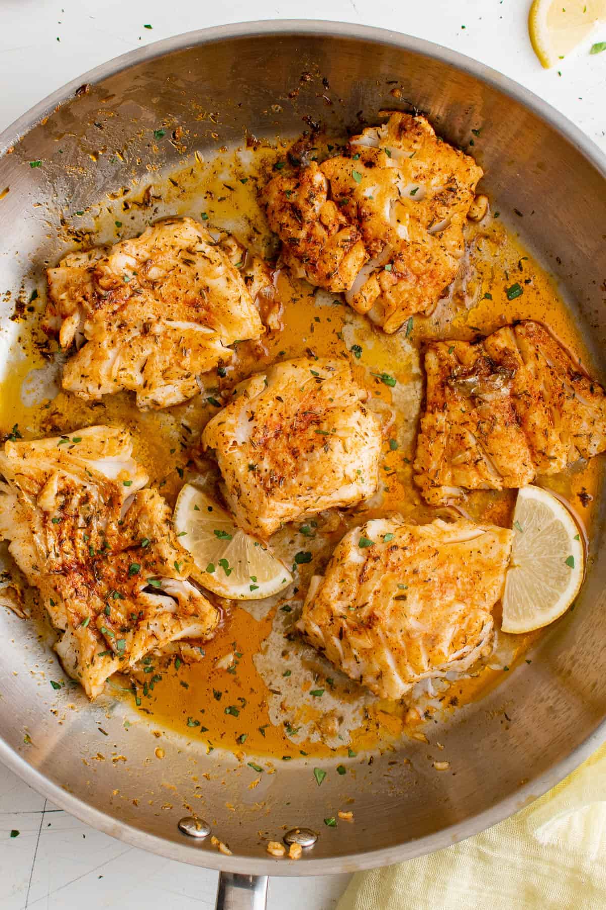 seared cod in a pan with lemon slices