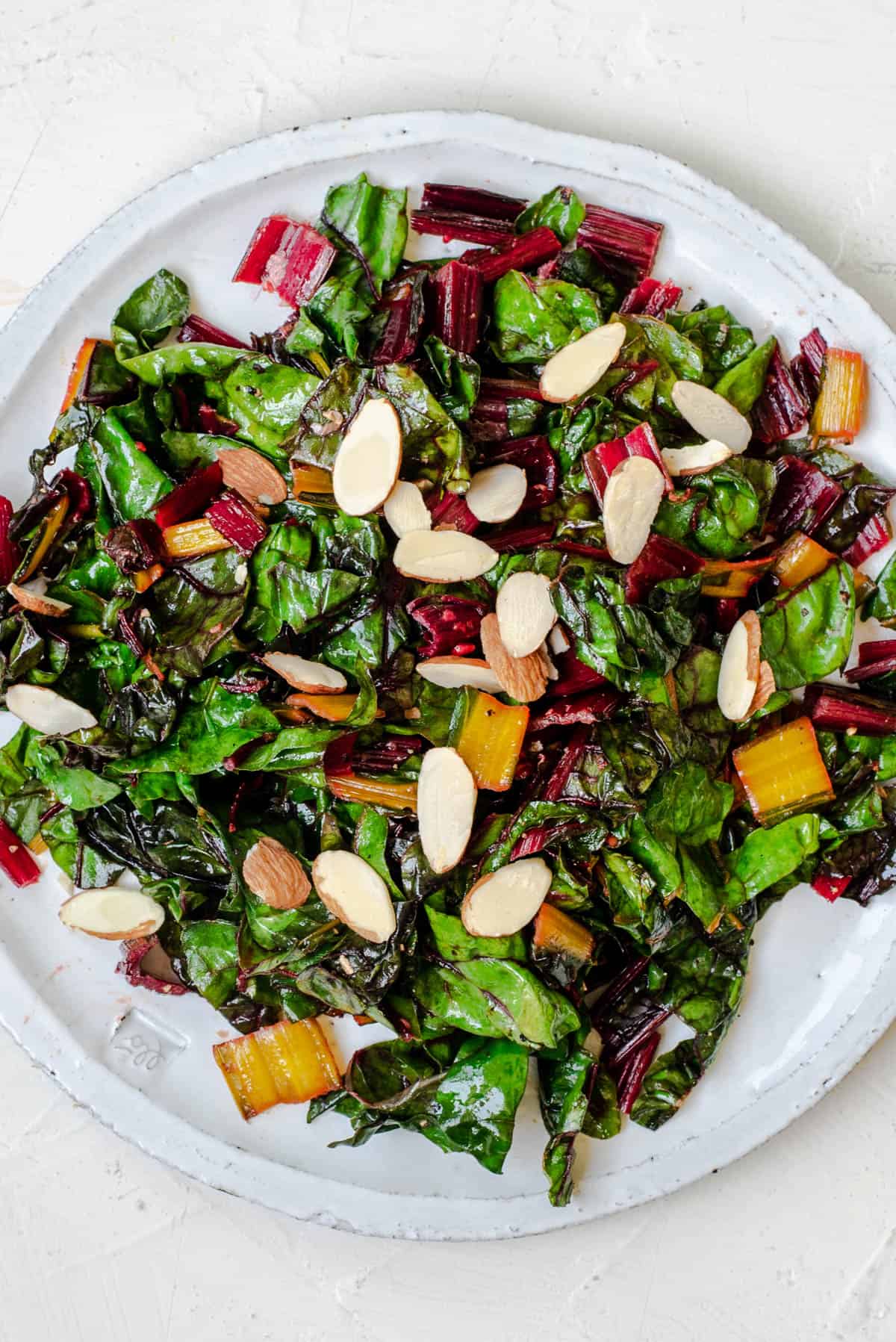 Sautéed swiss chard on a plate with sliced almonds on top.