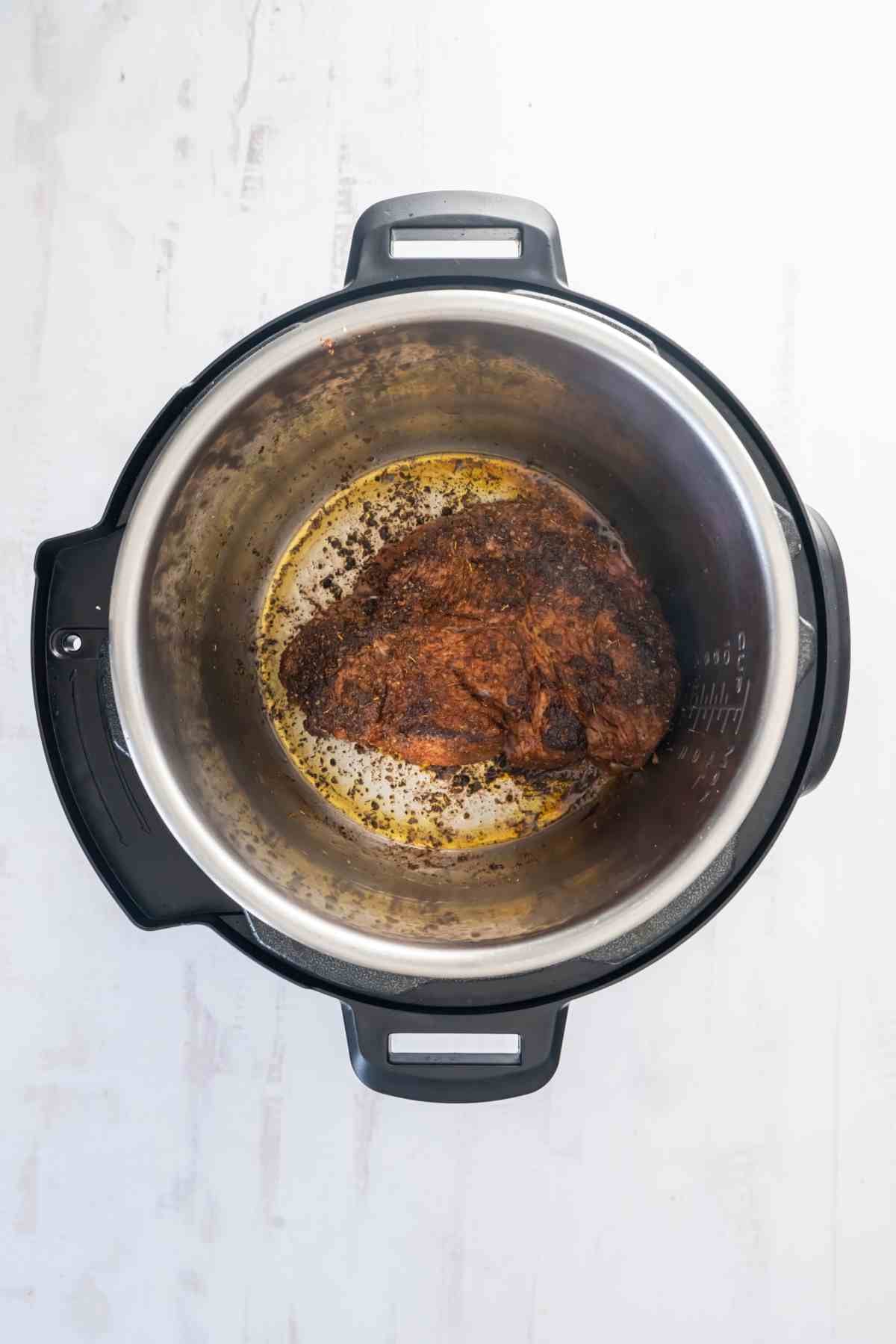 Seasoned chuck roast seared in the Instant Pot until browned on all sides.