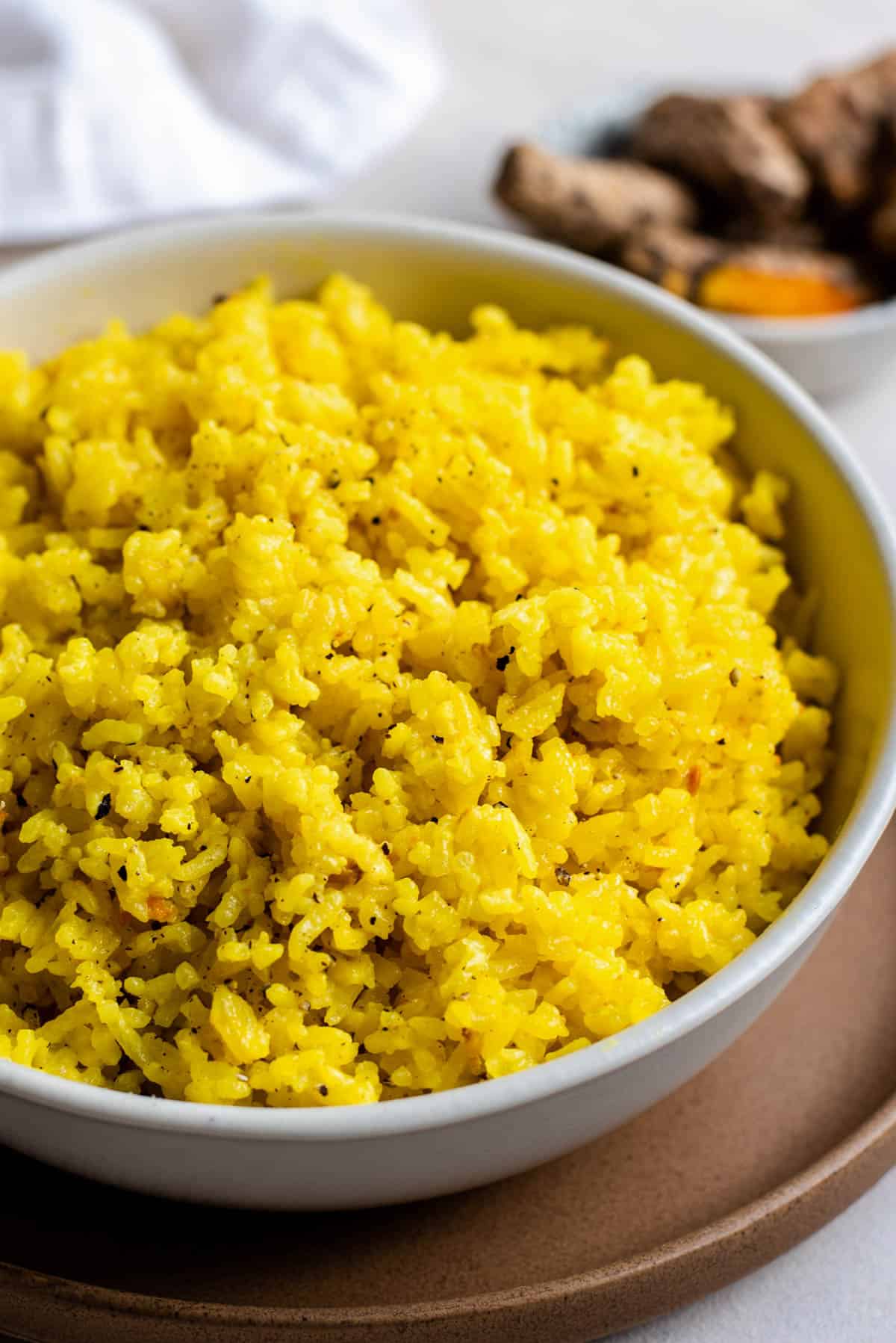 A large white bowl filled with fluffy turmeric coconut rice.