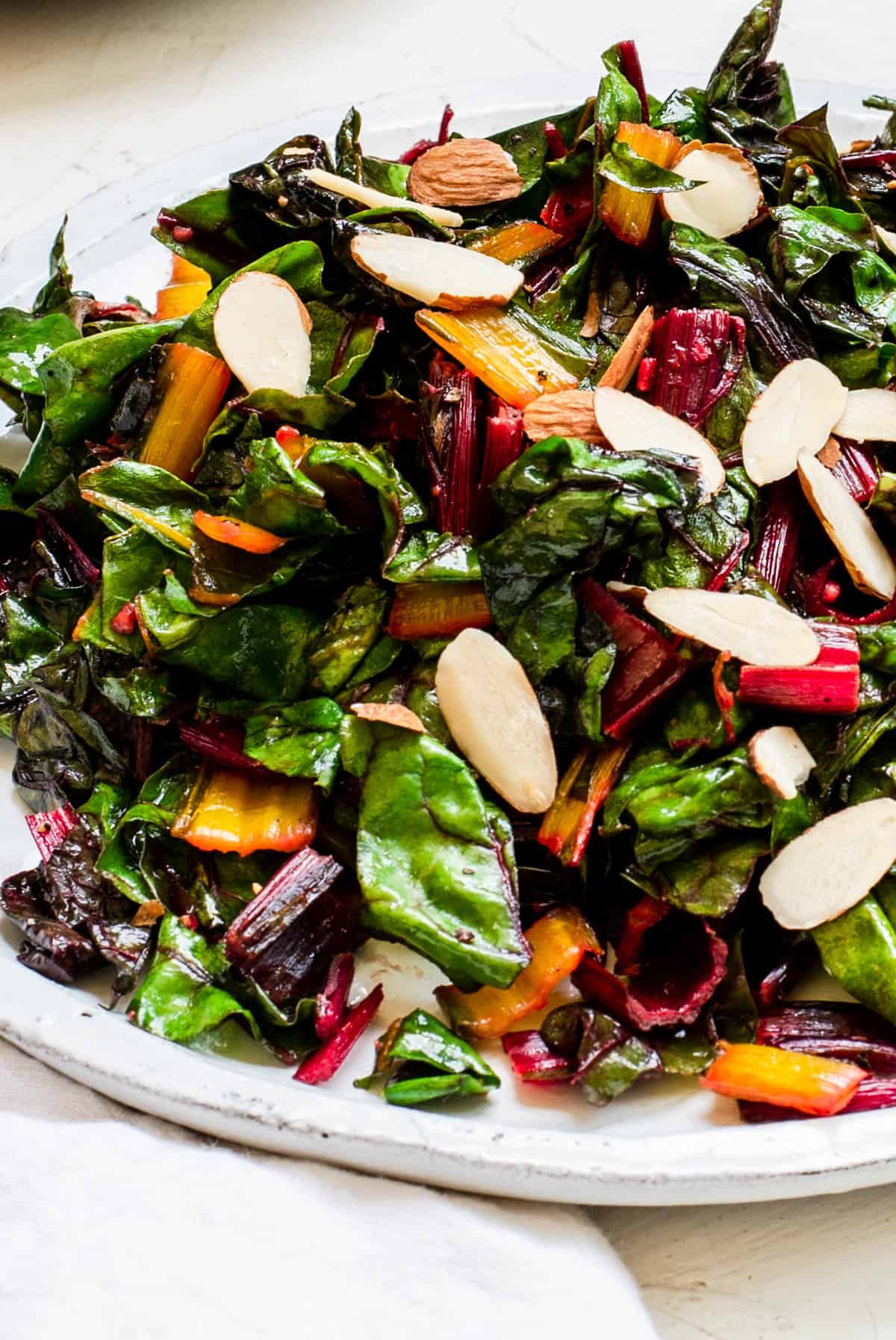 Sautéed Swiss chard on a white plate with a few sliced almonds on top. 