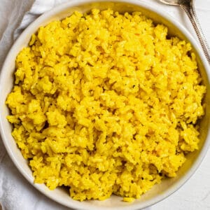 A large white bowl filled with cooked turmeric coconut rice.