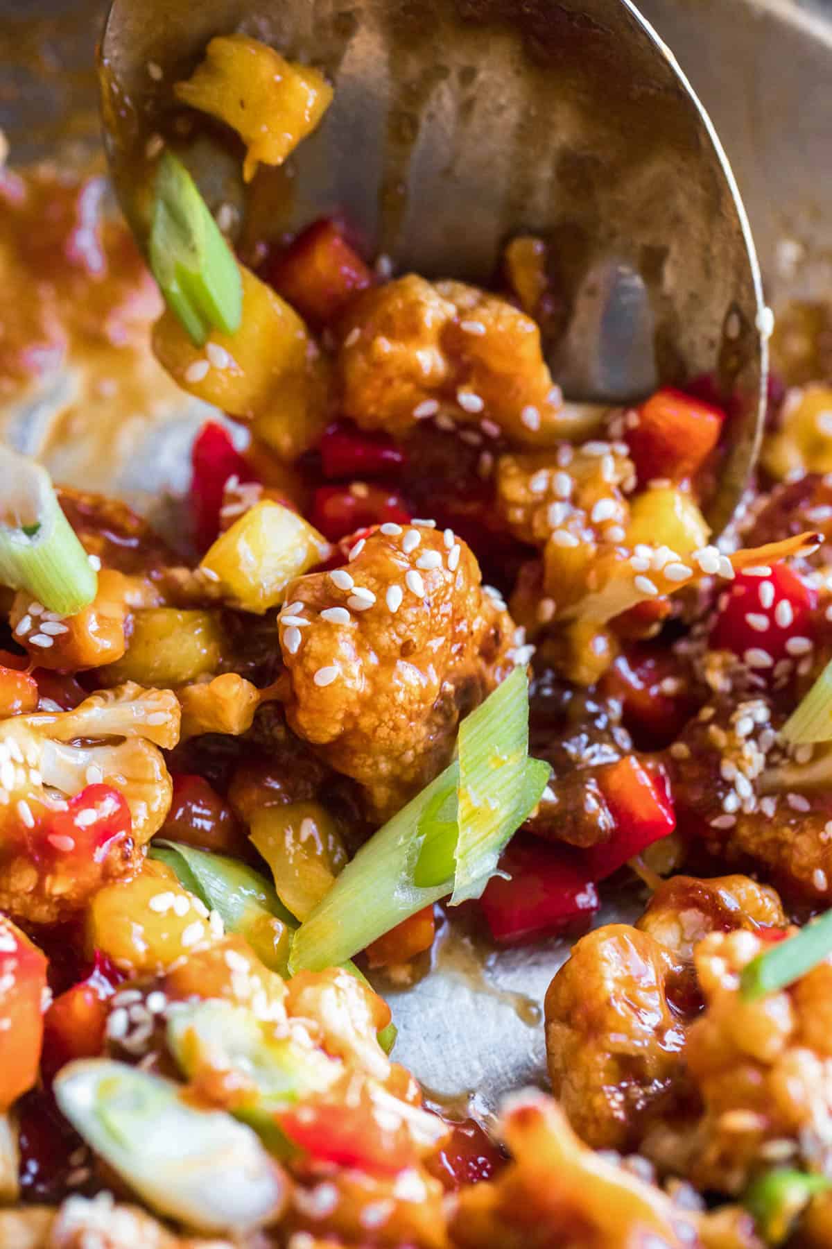 a spoon scooping cooked sweet and sour cauliflower