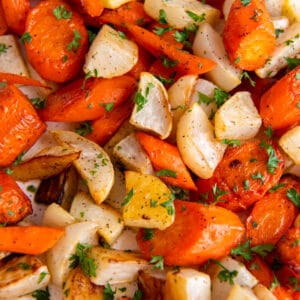 roasted turnips and carrots piles on a sheet pan with chopped parsley