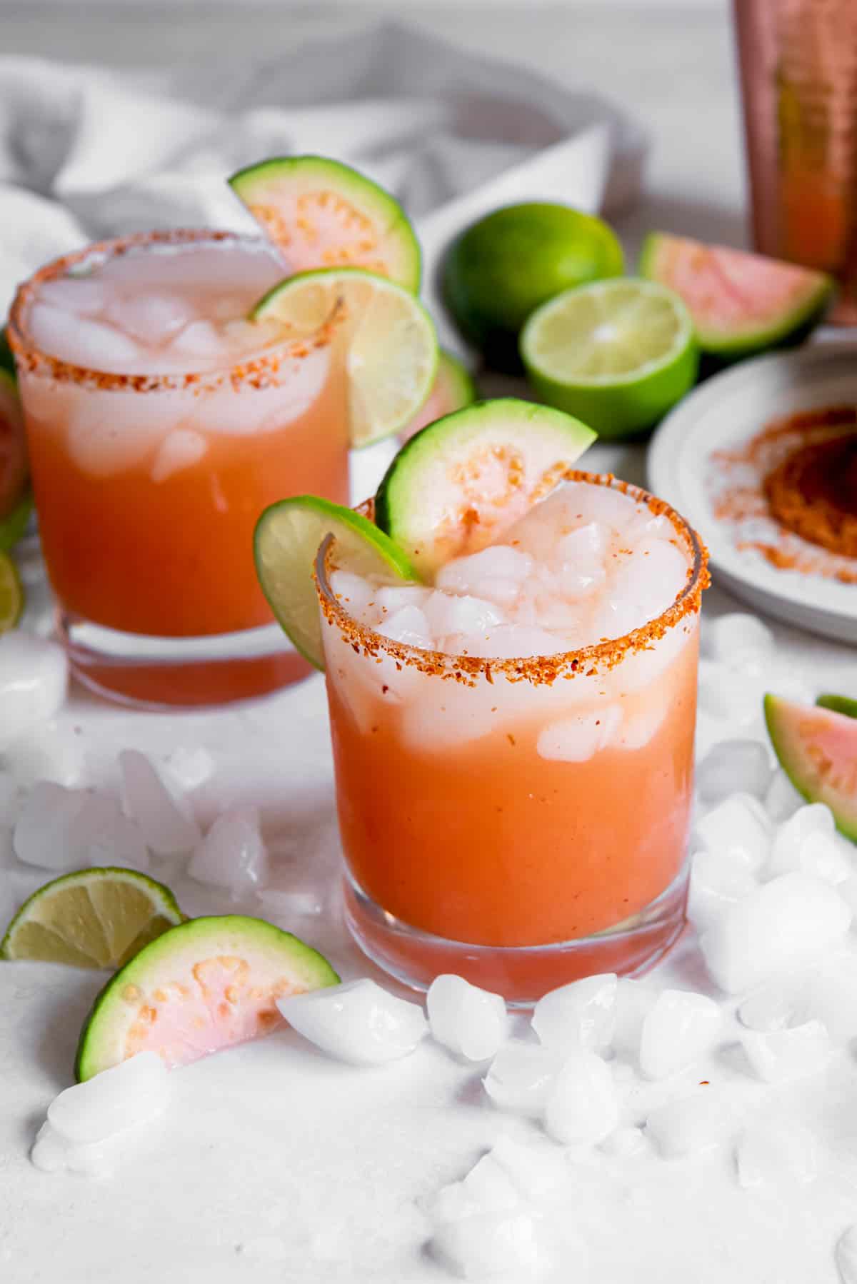 Two glasses filled with guava margaritas and ice.