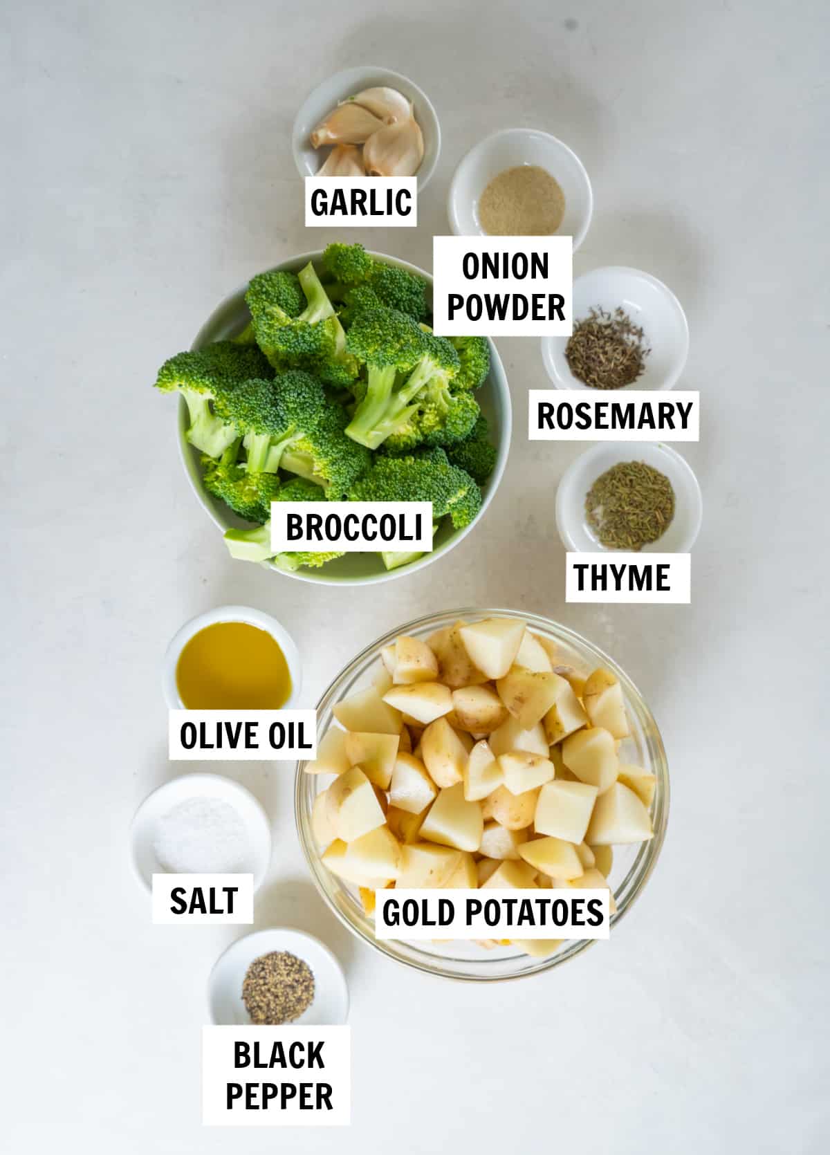 All of the ingredients for roasted potatoes and broccoli on a white countertop.