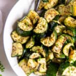 A white bowl filled with air fried zucchini for serving.