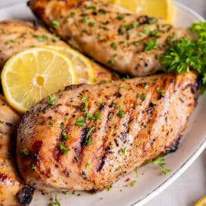 A plate layered with grilled lemon pepper chicken breasts.