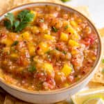 A bowl filled with fresh mango habanero salsa sitting next to tortilla chips.