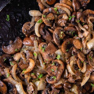 Sauteed mushrooms and onions in a black cast iron skillet after cooking.