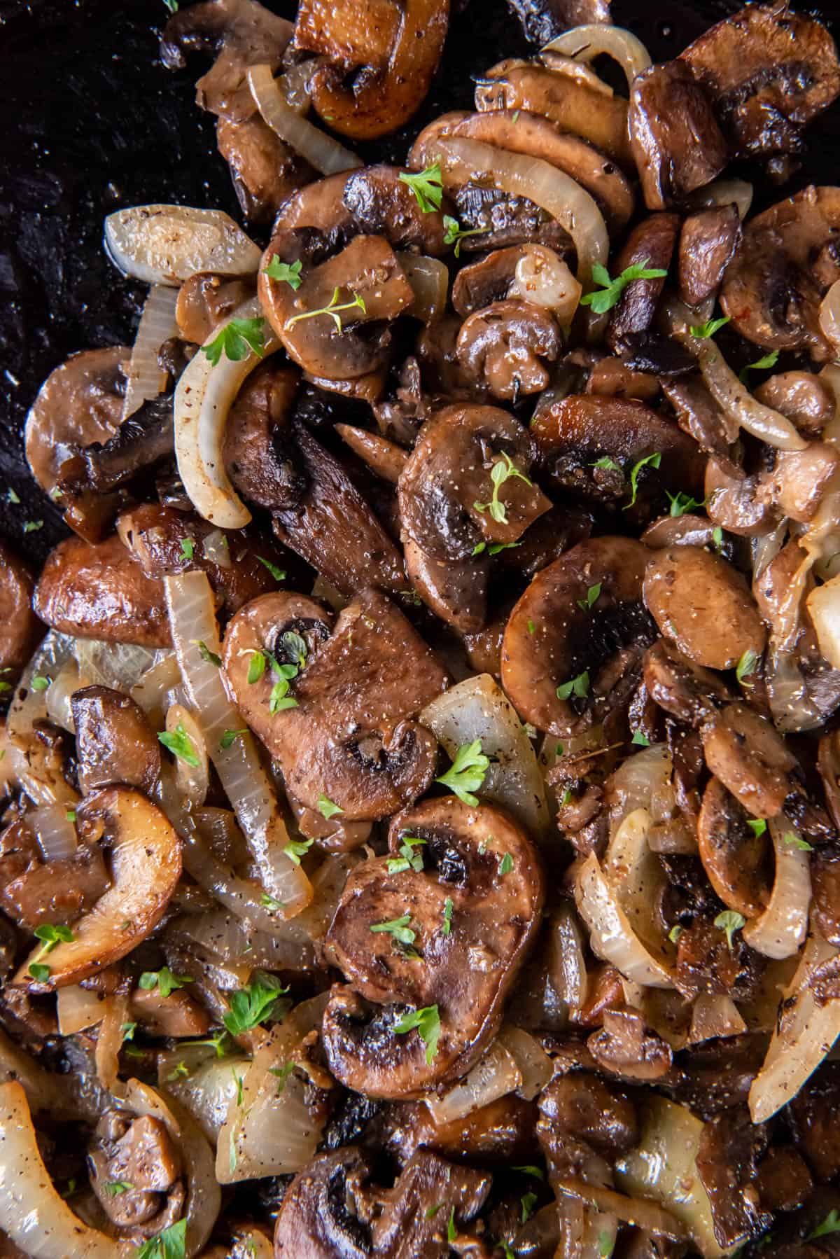 Cooked mushrooms and onions in a black cast iron skillet.