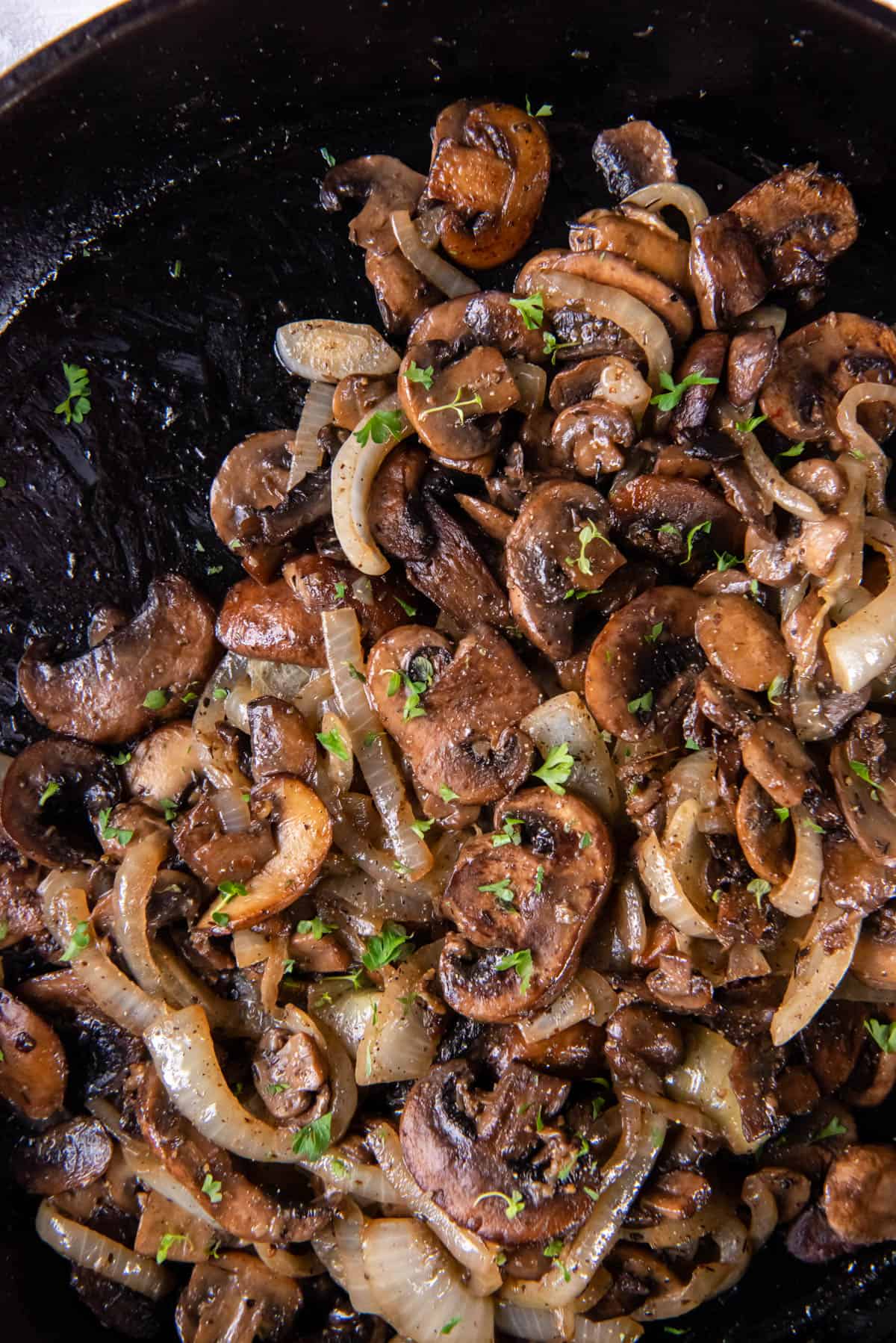 Sauteed mushrooms and onions in a black cast iron skillet after cooking.