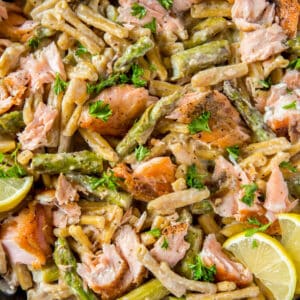 Cooked pasta with salmon, asparagus and a creamy lemon sauce in a skillet ready for serving. Freshly chopped parsley is garnished on top.