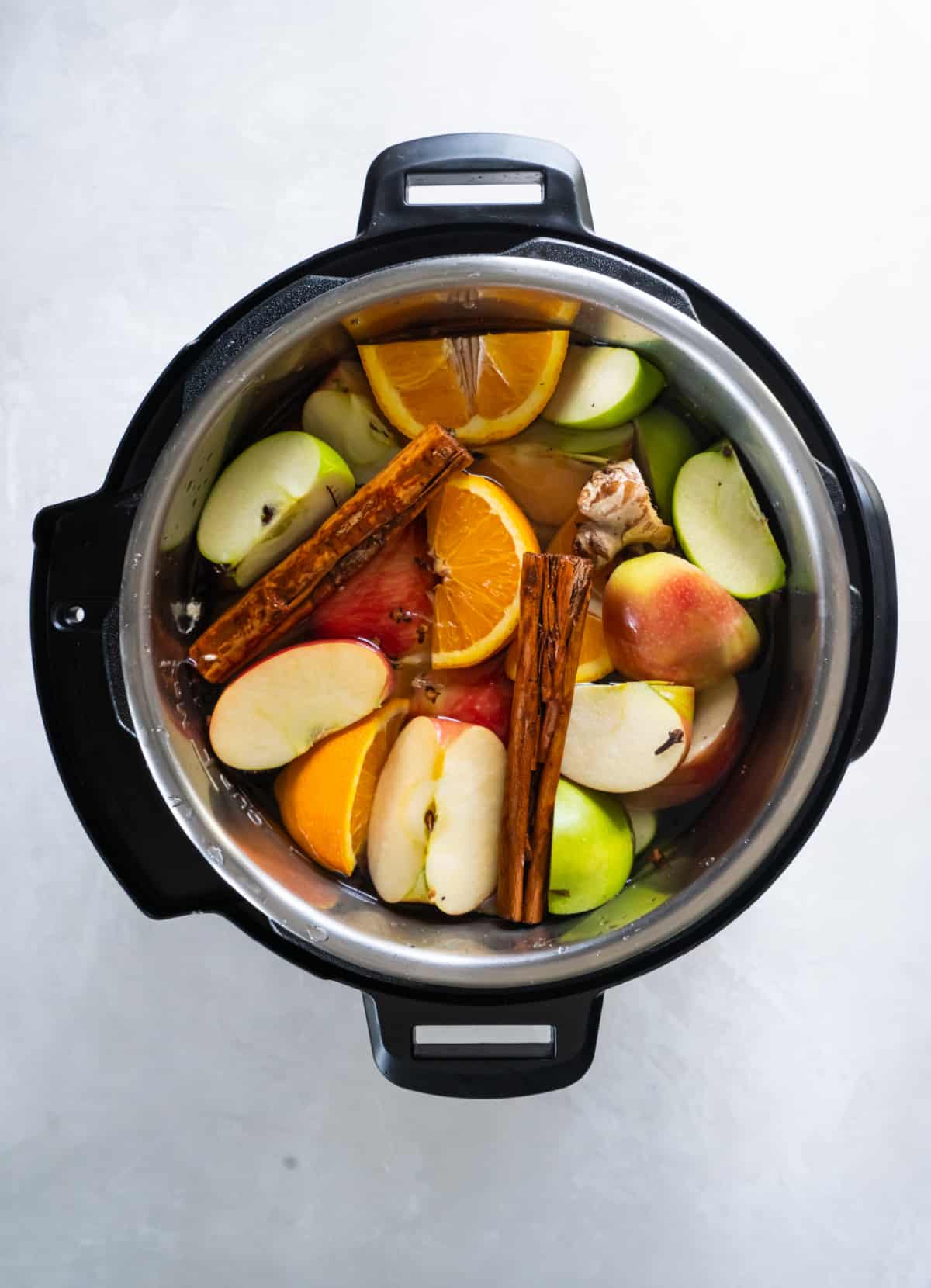 All of the ingredients for the apple cider in an instant pot before cooking.