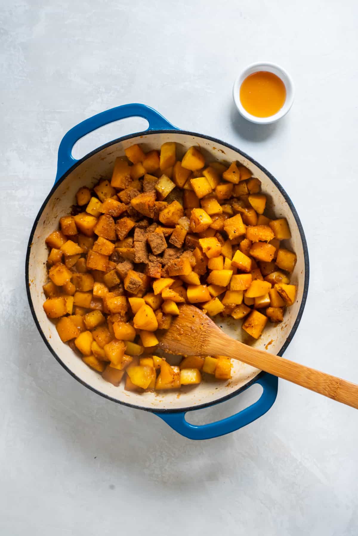 Sauteed butternut squash in a skillet sprinkled with ground cinnamon.