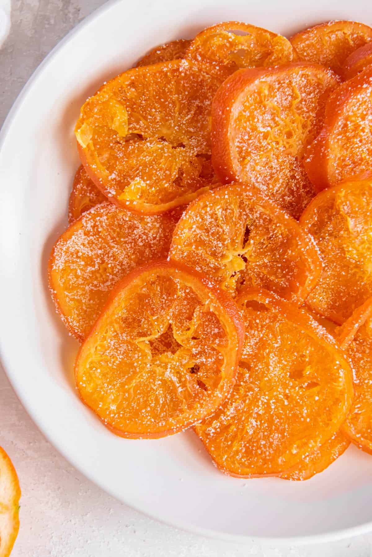 Candied orange slices piled on top of a white plate in a circle pattern.