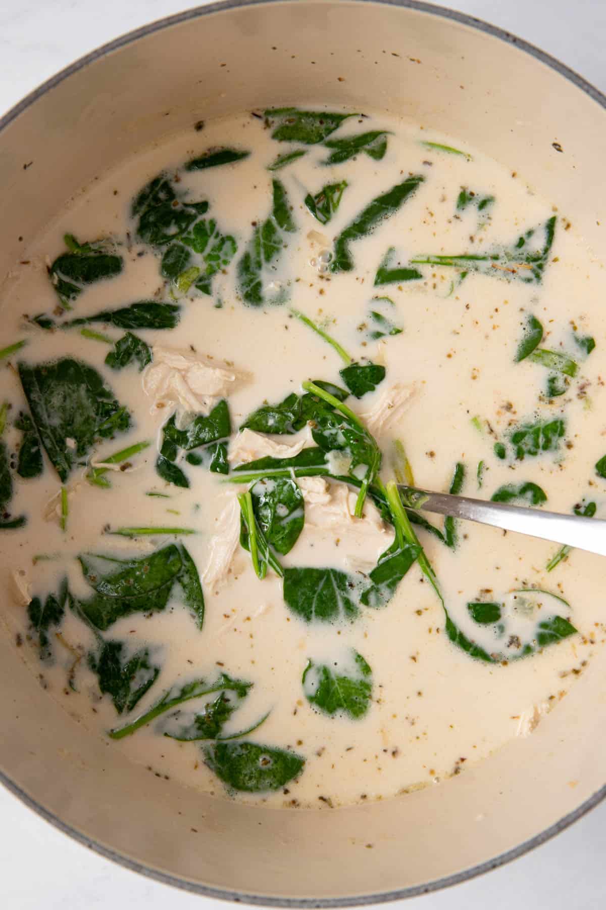 Creamy chicken florentine soup in a large pot after cooking. 