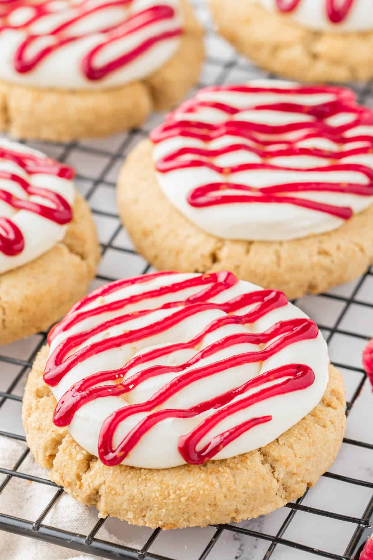 Graham cracker cookies with cream cheese frosting and raspberry drizzle.