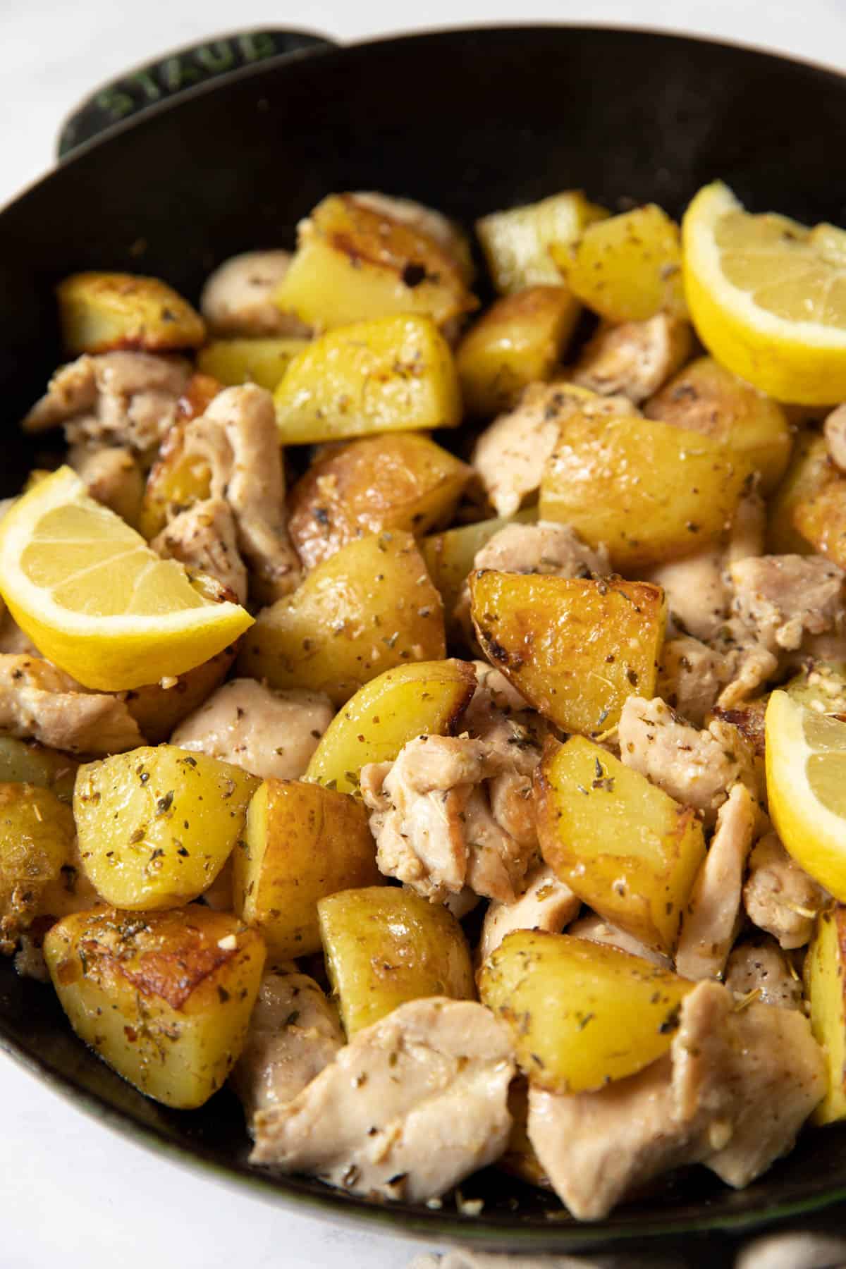 Chicken and potatoes in a skillet for serving.