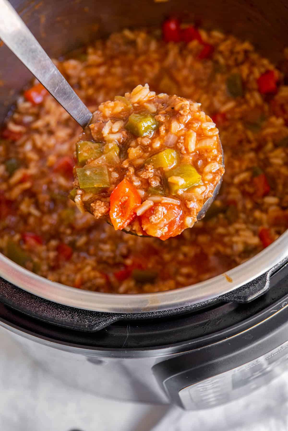 A soup ladle scooping out the stuffed pepper soup from the instant pot bowl.
