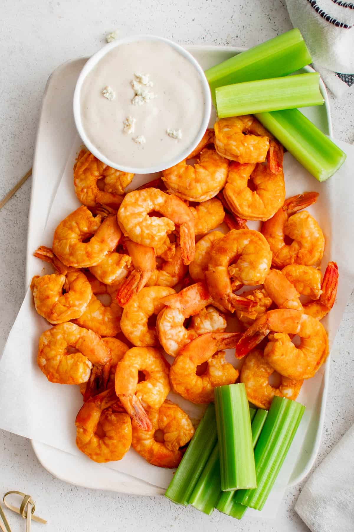 A white plate filled with buffalo shrimp and celery.
