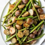 Oven roasted green beans and potatoes on a oval round plate ready for serving.