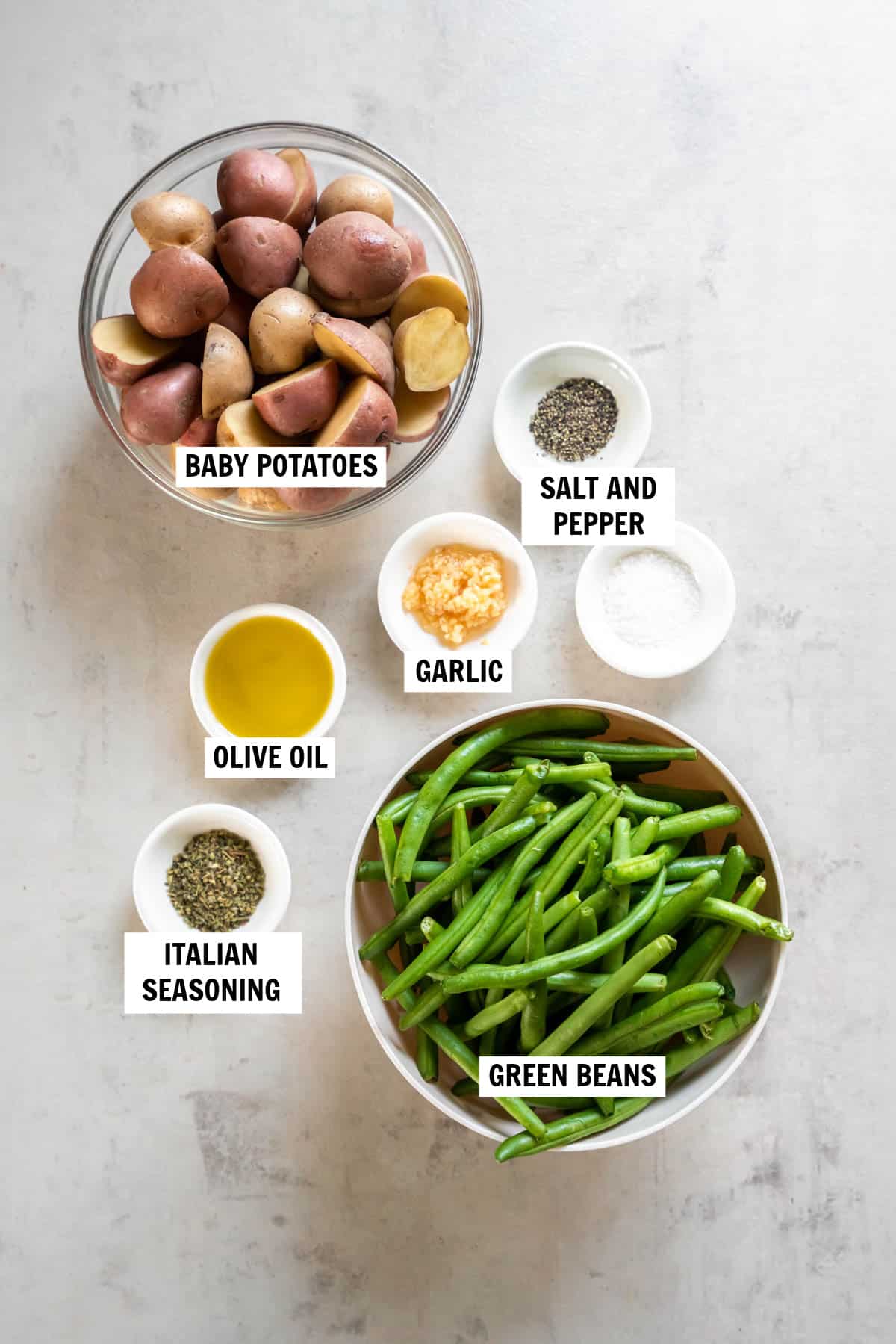 All of the ingredients for roasted green beans and potatoes on a white countertop.