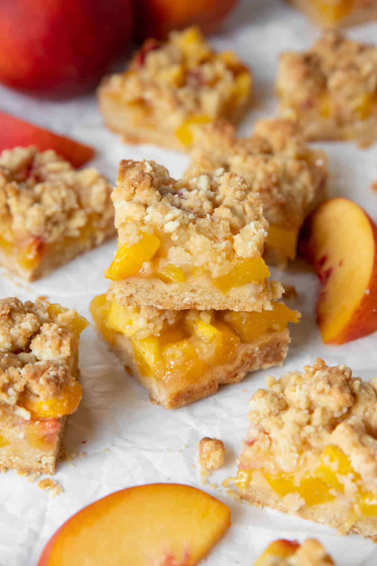 Two peach bars sit on top of each other with the other peach bars on white parchment paper.