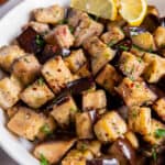 A white serving bowl with sautéed eggplant.