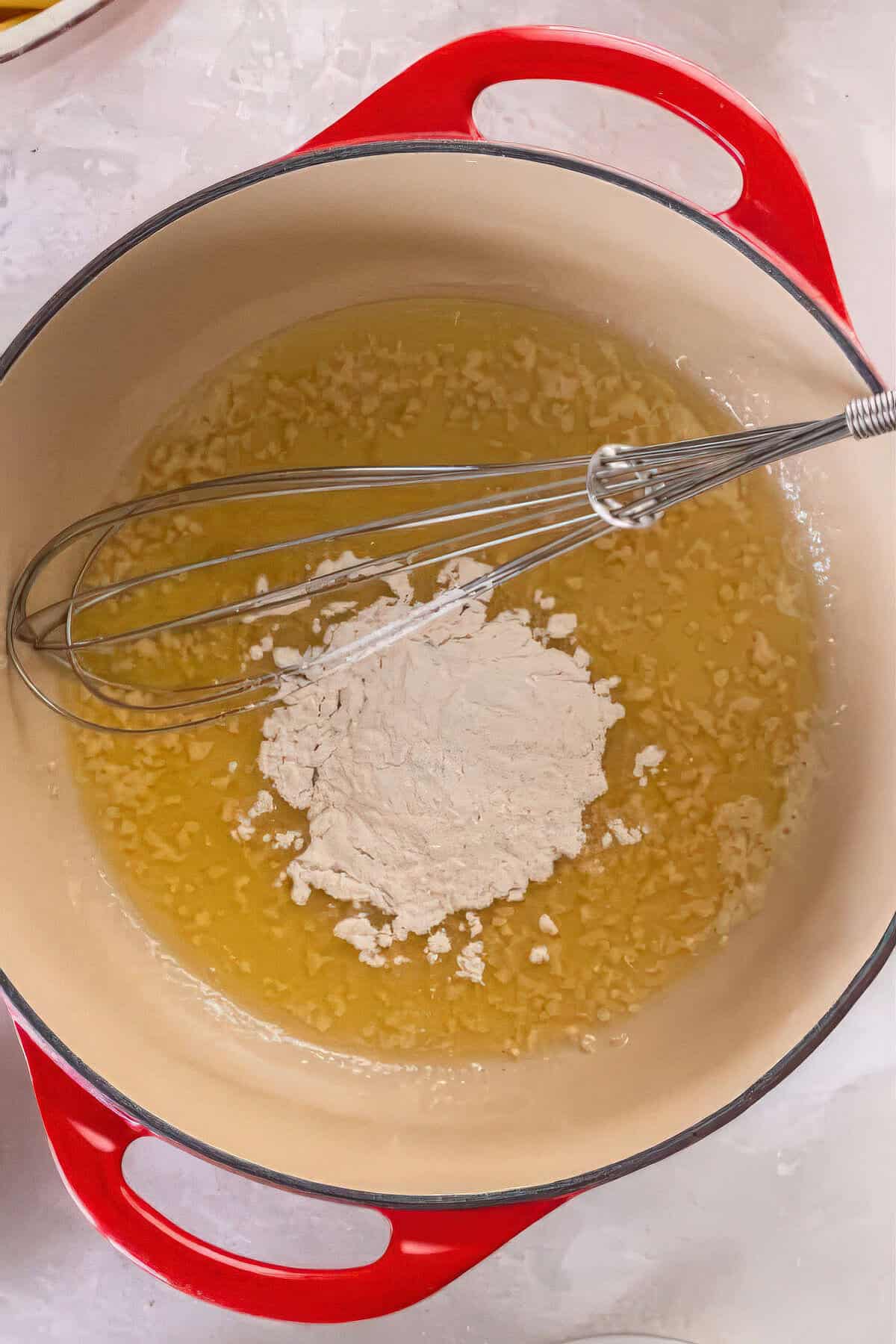 Melted butter and minced garlic in a Dutch oven with flour added to begin making Alfredo sauce.