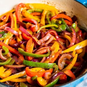 Fajita veggies cooked in a blue enameled cast iron skillet that is ready for serving.