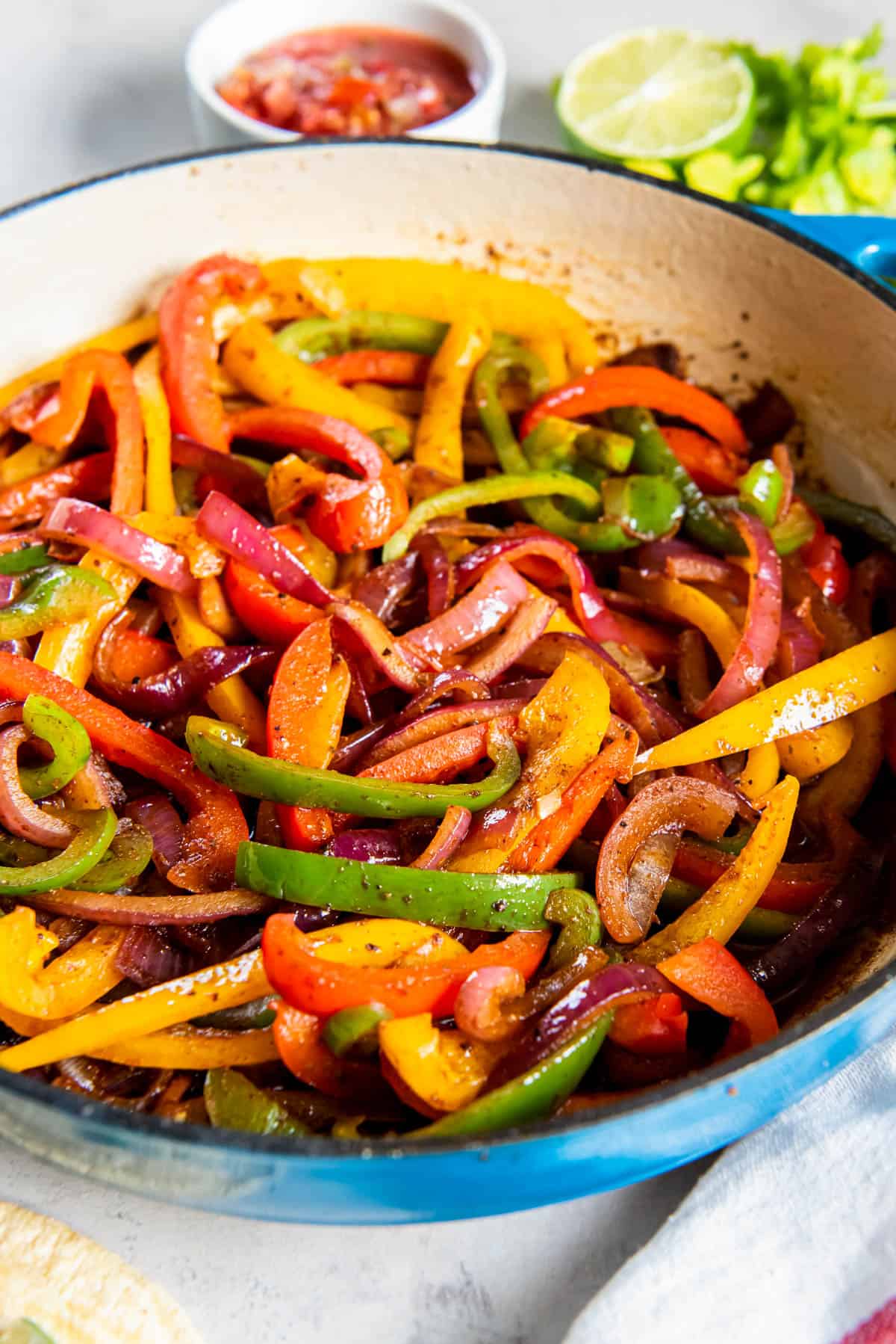 Fajita veggies cooked in a blue enameled cast iron skillet that is ready for serving.