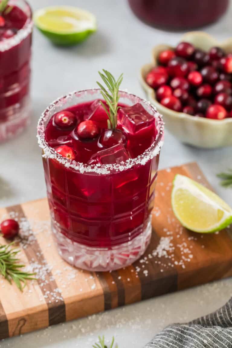 Sparkling cranberry mocktail in a glass on a small cutting board for serving.