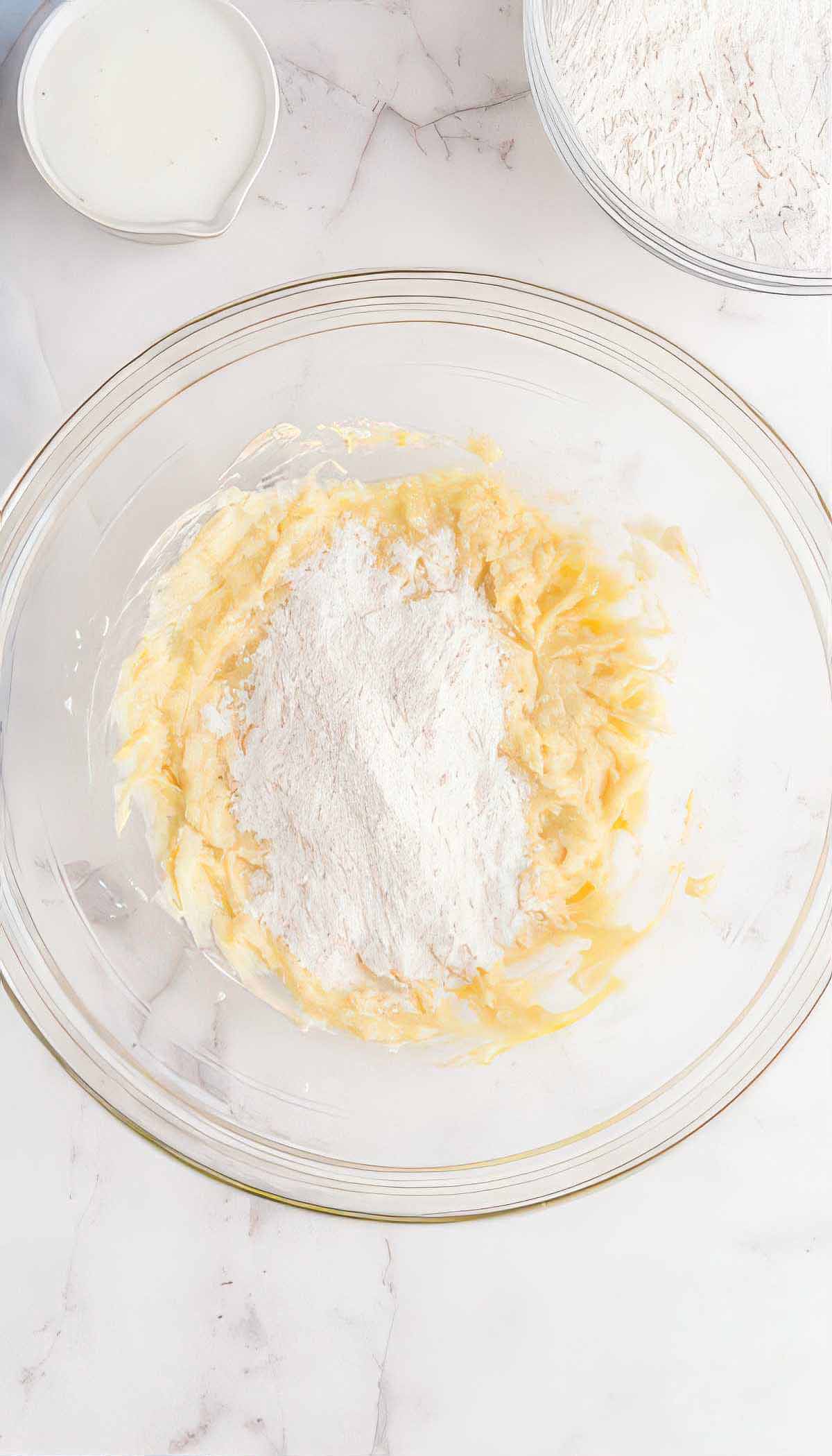 Dry ingredients being added to butter mixture for blueberry breakfast cake batter.