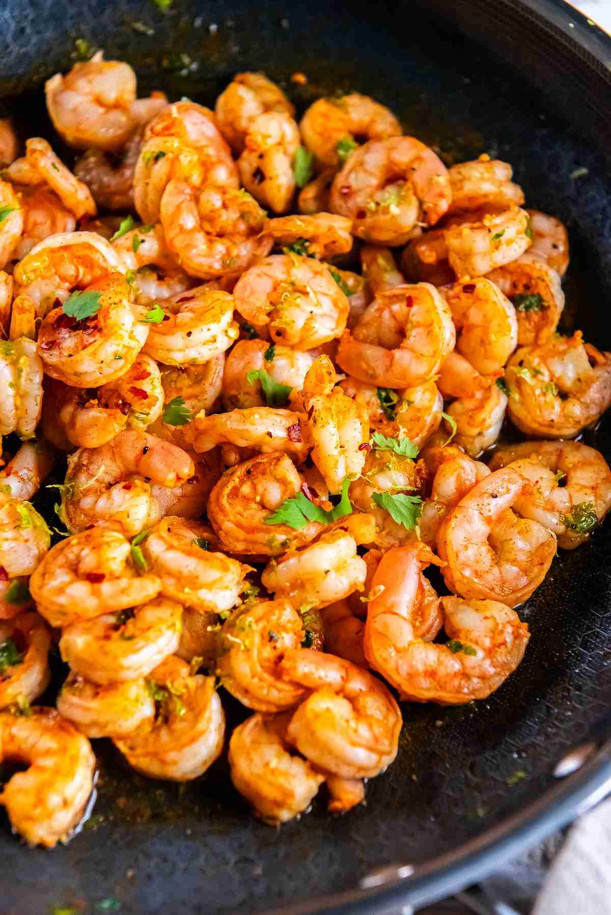 Cooked shrimp in a skillet with chili lime seasoning and cilantro for shrimp tacos