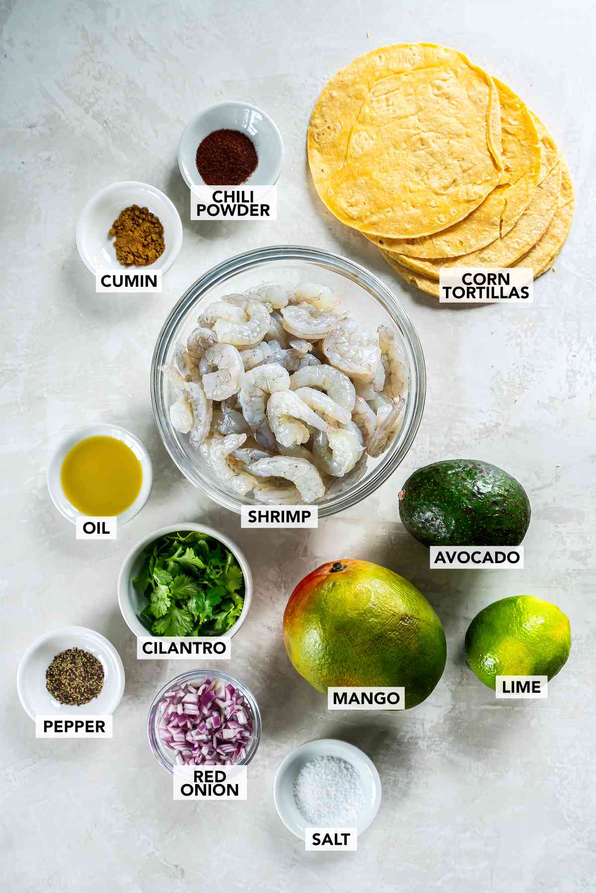 Ingredients for cilantro lime shrimp tacos including shrimp, mango, avocado, lime, cilantro, and tortillas