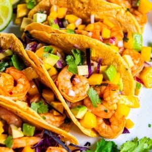 Close up of shrimp tacos with mango avocado salsa, red onion, and fresh cilantro