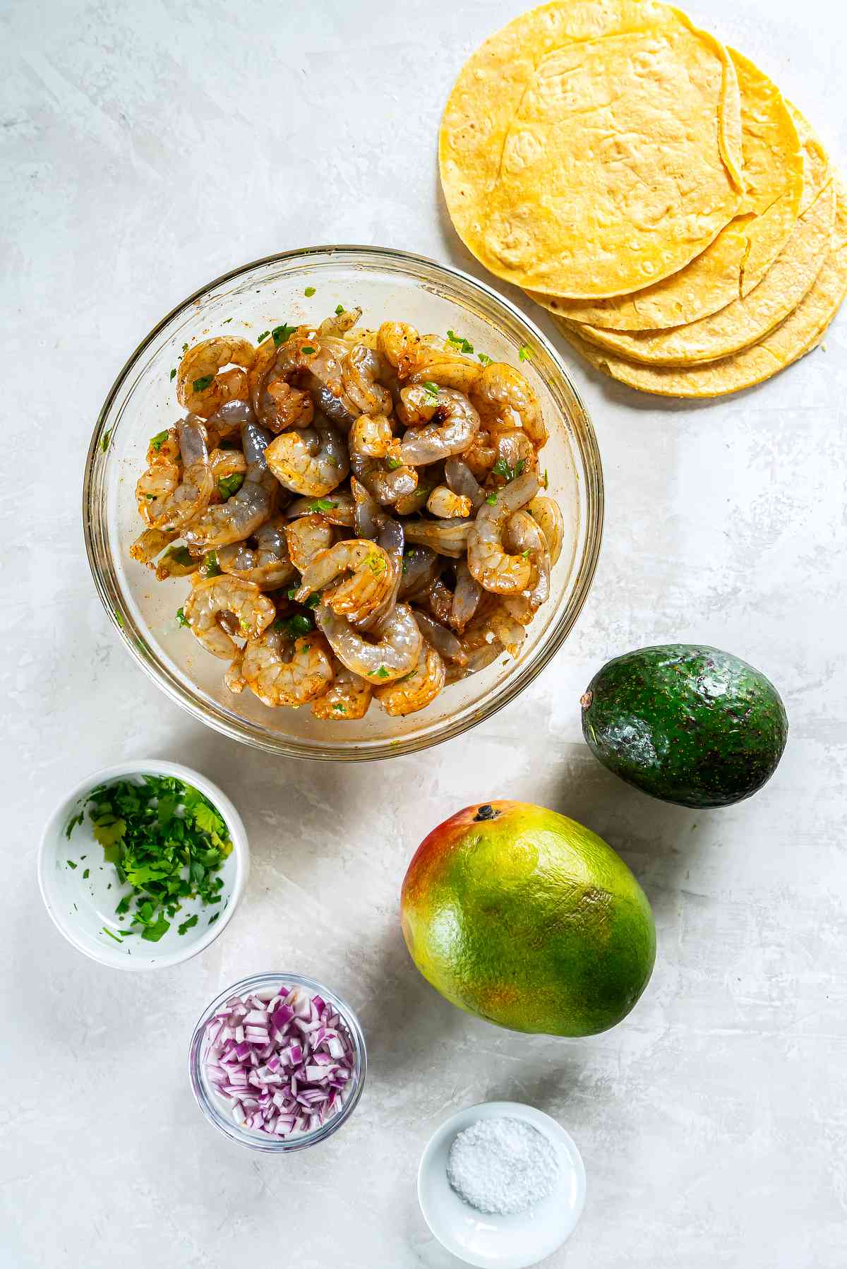 Raw shrimp coated in cilantro lime marinade with spices in a bowl for shrimp tacos