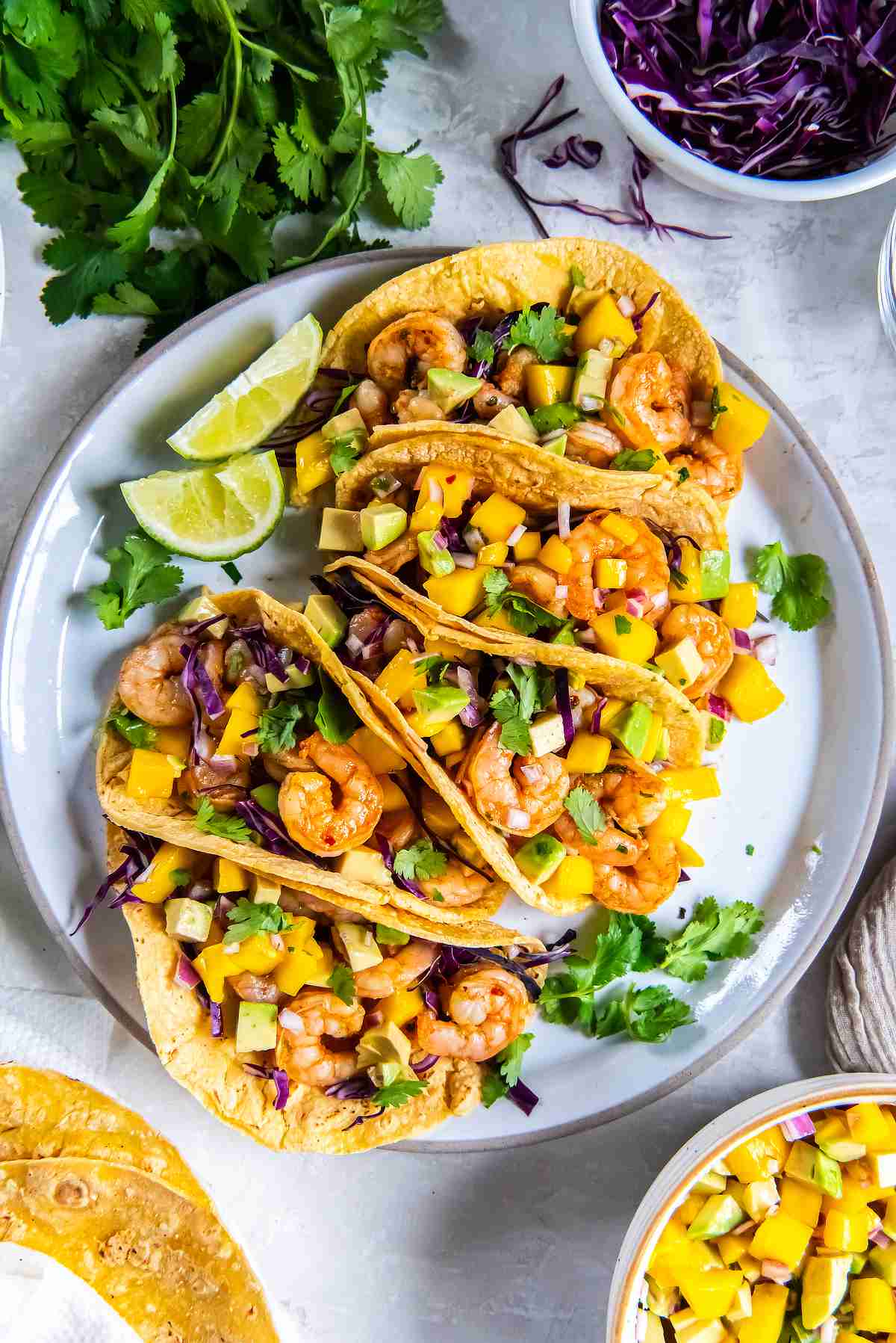 Cilantro lime shrimp tacos topped with mango avocado salsa and fresh cilantro on a plate