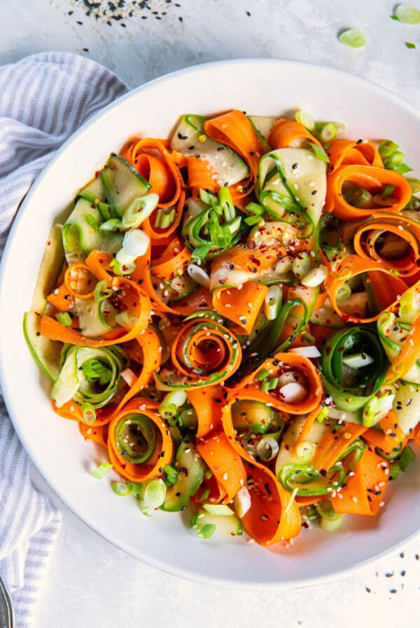 Overhead shot of finished carrot cucumber salad with scattered sesame seeds.