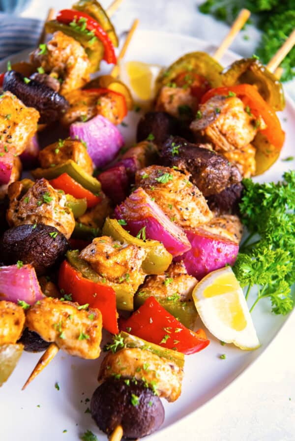 Baked Chicken Skewers with colorful veggies and herbs on a white platter.