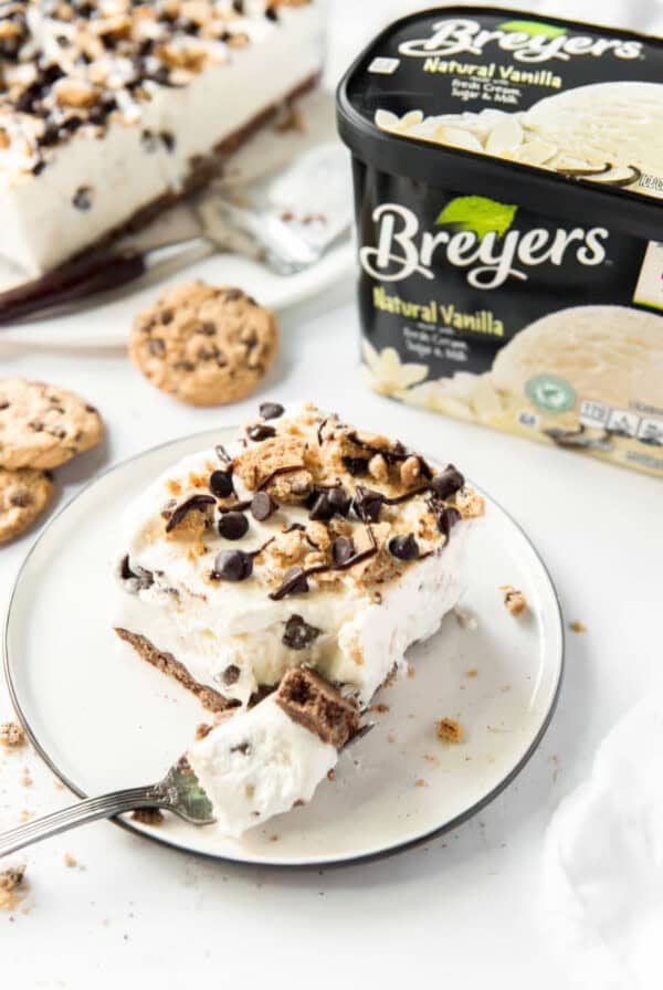 Slice of Cookie Cream Ice Cream Cake on a white plate with a bite on a fork